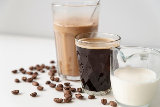 カフェオレとブラックコーヒー、ミルクが入ったグラスとコーヒー豆のイメージ