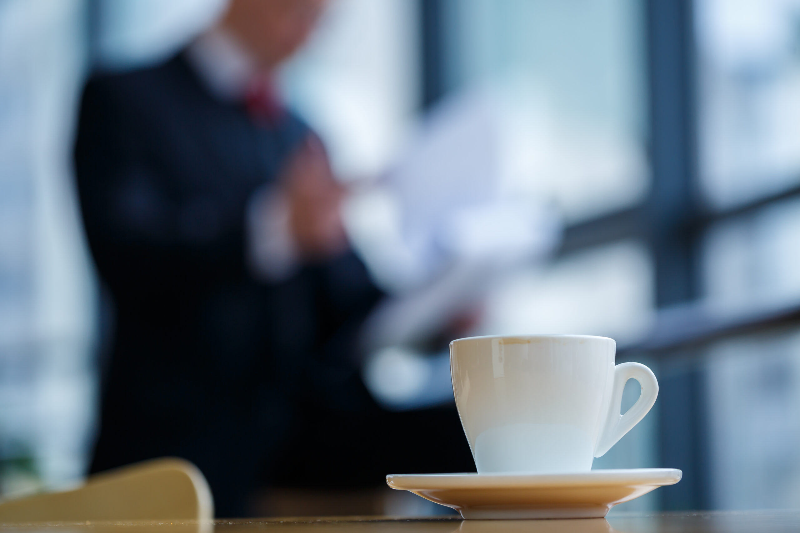 書類を見るスーツ姿の男性とコーヒーカップ