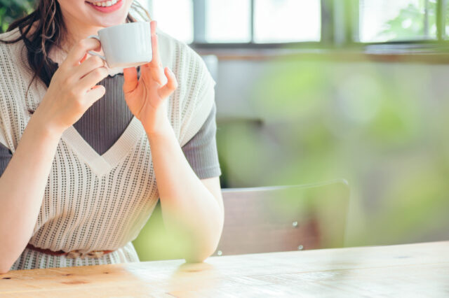 コーヒーカップをもって微笑んでる女性